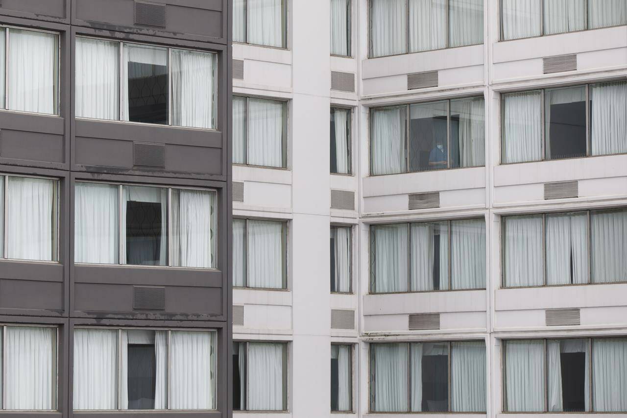 A hotel worker is seen in a hotel window in Mississauga, Ont. by the Pearson International Airport on Monday, Feb. 22, 2021 as new air travel rules come into effect in Canada. THE CANADIAN PRESS/Cole Burston