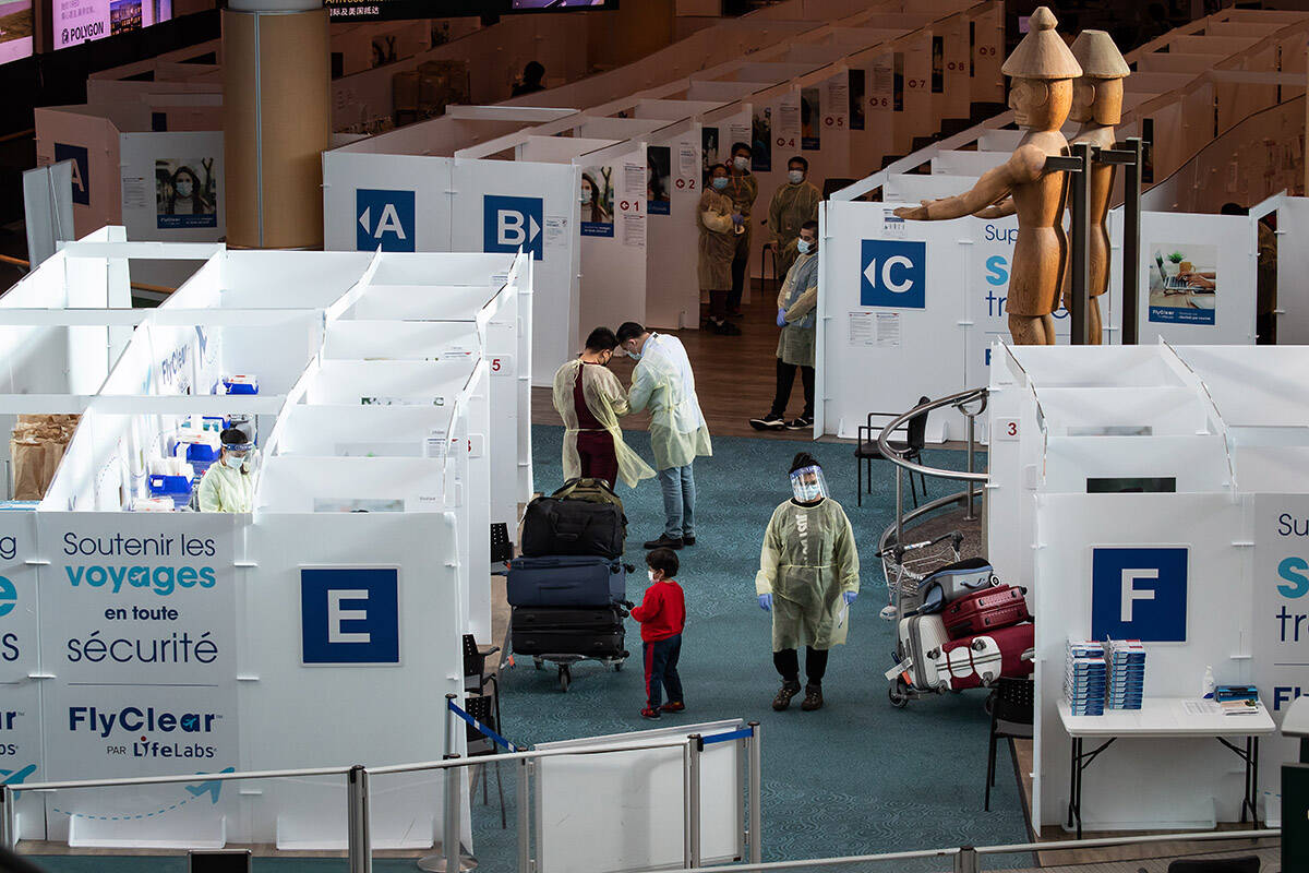 A Lifelabs employee walks past a child waiting for his parents in the COVID-19 testing area for arriving international passengers at Vancouver International Airport, in Richmond, B.C., on Thursday, December 2, 2021. All air travellers entering Canada, except for those coming from the U.S., are now required to be tested for COVID-19 upon arrival and isolate until they get their results, even if they are fully vaccinated against the virus. THE CANADIAN PRESS/Darryl Dyck