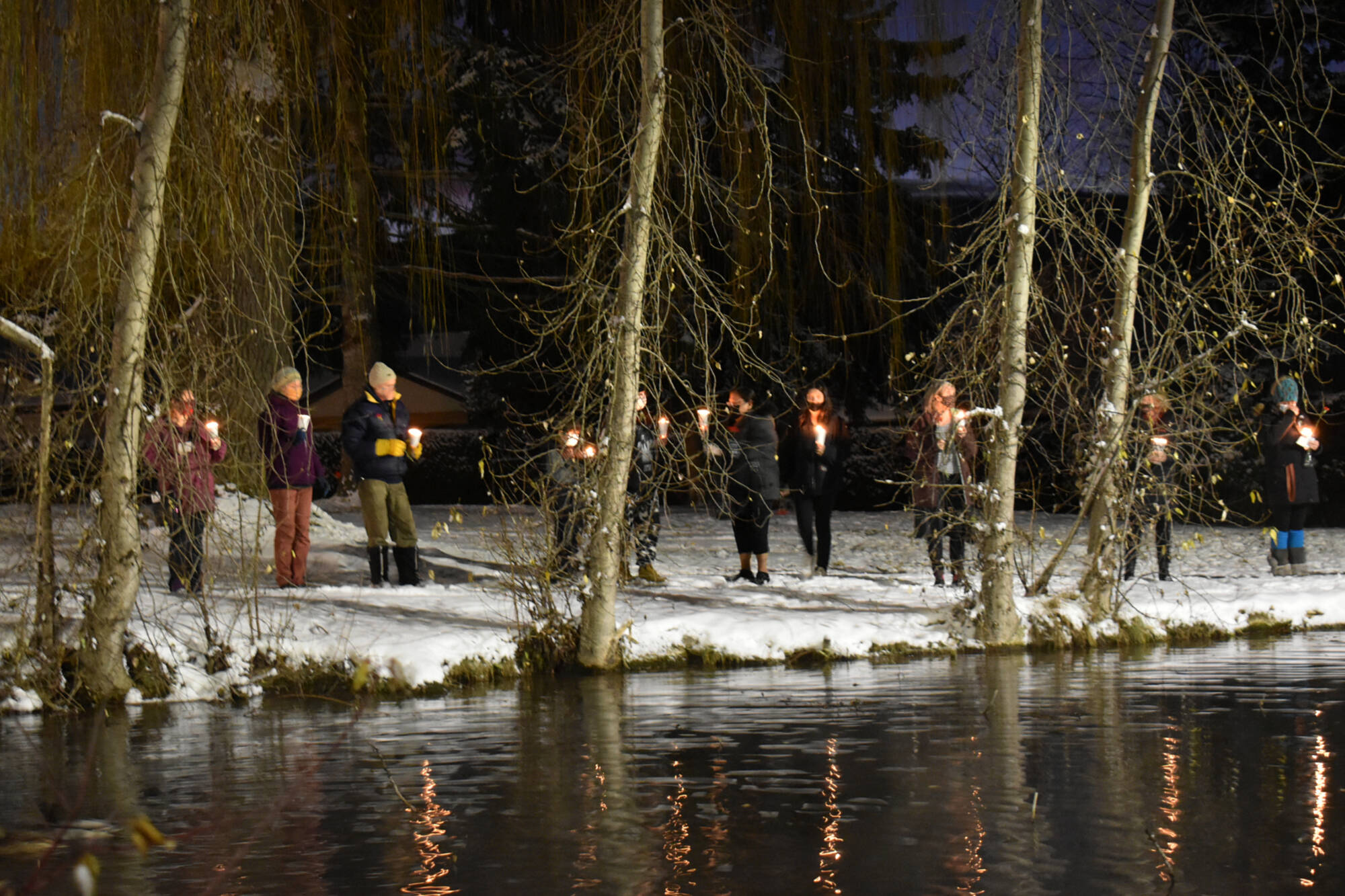 People gather at the edge of the pond at the Salmon Arm campus of Okanagan College on Dec. 6 during the United Against Violence Against Women candlelight vigil held to mark the 1989 massacre of 14 women at Ecole Polytechnique in Montreal as well as to remember and bear witness to the women murdered and missing in the Okanagan-Shuswap and beyond. (Martha Wickett-Salmon Arm Observer)
