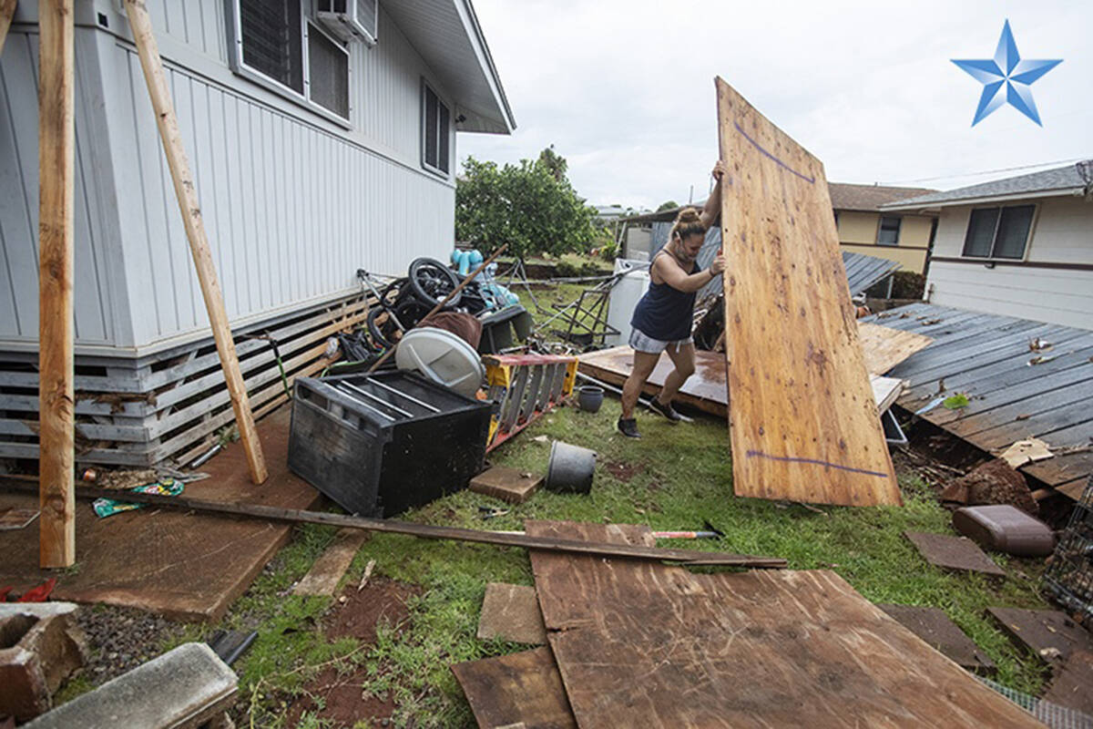 Shaney Hoyhoy lifted a piece of plywood off a downed fence at her Nanakai Place home after heavy rains flooded her Pearl City neighborhood on Monday. (Cindy Ellen Russell/Honolulu Star-Advertiser)