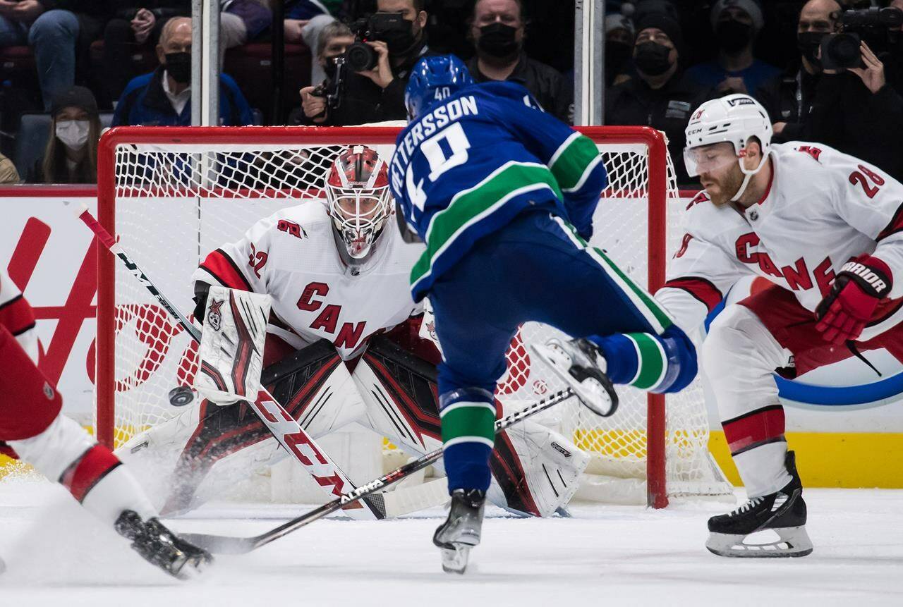 Vancouver Canucks’ Elias Pettersson (40), of Sweden, scores against Carolina Hurricanes goalie Antti Raanta (32), of Finland, as Ian Cole (28) defends during second period NHL hockey action, in Vancouver, B.C., Sunday, Dec. 12, 2021. THE CANADIAN PRESS/Darryl Dyck