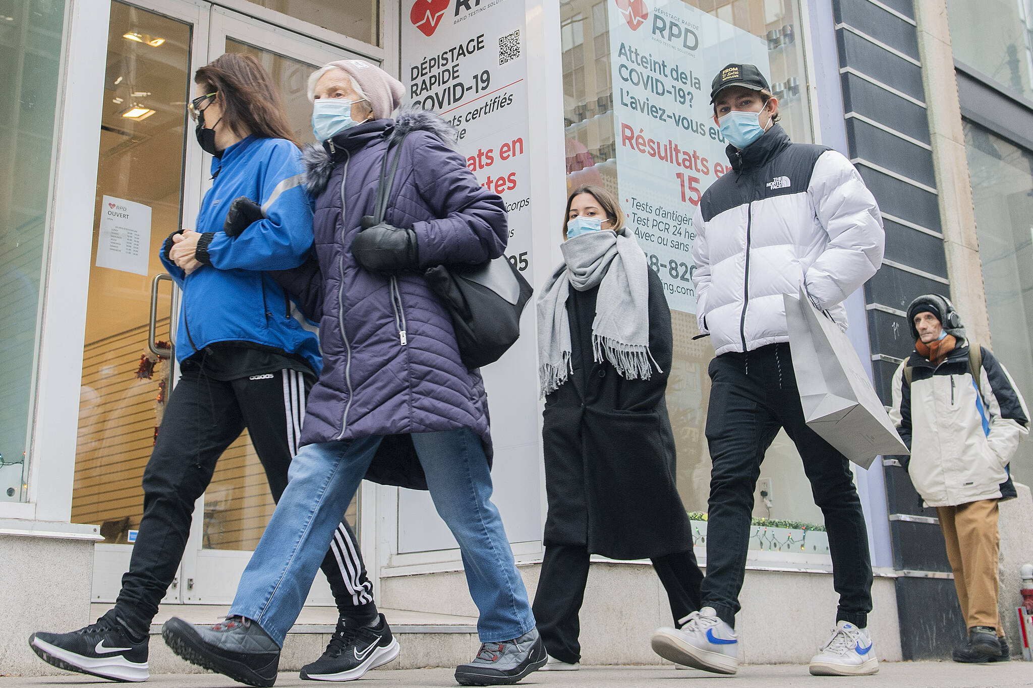 People walk by a COVID-19 rapid testing business in Montreal, Saturday, Dec. 4, 2021. THE CANADIAN PRESS/Graham Hughes