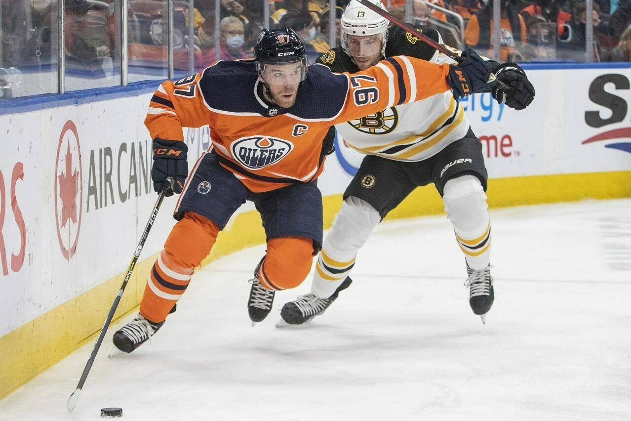 Boston Bruins’ Charlie Coyle (13) chases Edmonton Oilers’ Connor McDavid (97) during second period NHL hockey action in Edmonton, Alta., on December 9, 2021. THE CANADIAN PRESS/Amber Bracken
