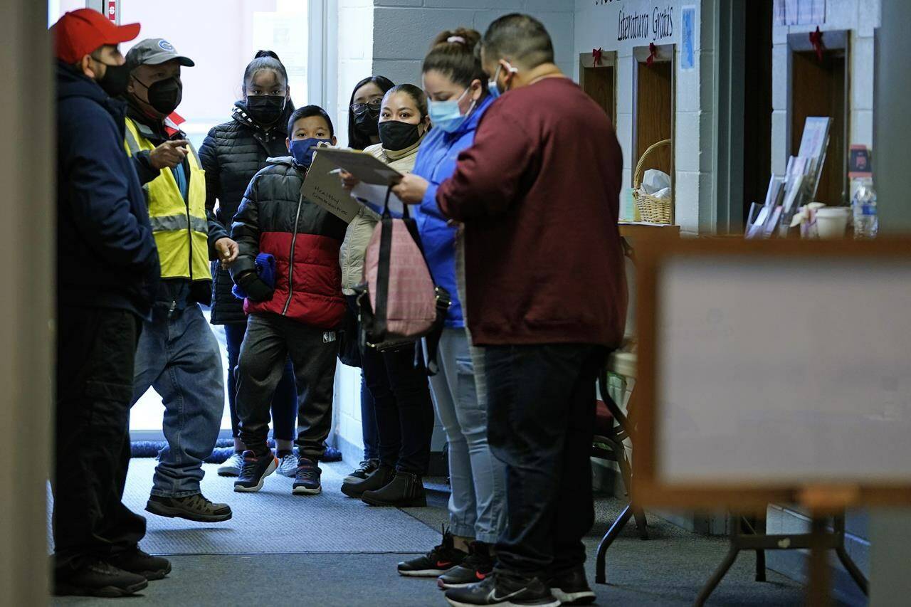 FILE - Kids and adults wait for their booster or second dose of COVID-19 vaccine at Northwest Community Church in Chicago, Saturday, Dec. 11, 2021. The new omicron coronavirus mutant speeding around the world may bring another wave of chaos, threatening to further stretch hospital workers already struggling with a surge of delta cases and upend holiday plans for the second year in a row. (AP Photo/Nam Y. Huh, File)