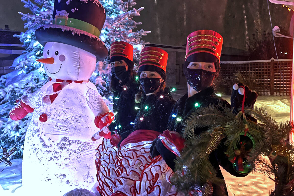 (L-R) Les Folles Jambettes’ Vanessa Reyes-Golding, Sarah Leslie and Melanie Shenstone pose for a photo next to a family of snow people displayed at a home on 17th Avenue, near the intersection of 77th Avenue on Saturday, Dec. 18. Photo: Laurie Tritschler