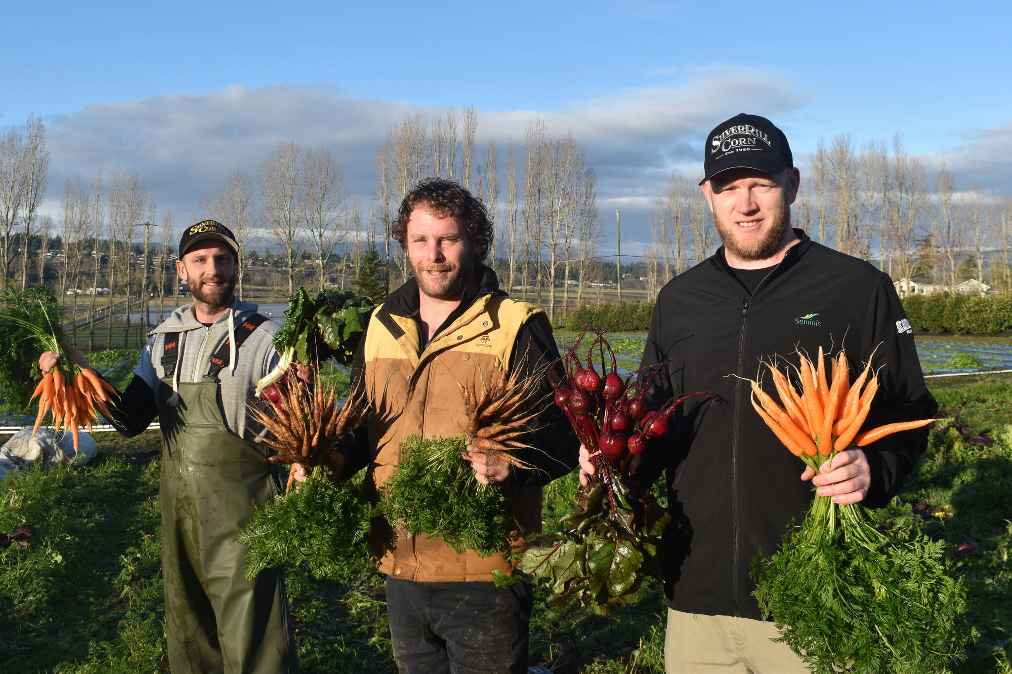 Paul Davidson, left, of Paul’s Farm Stand, Andrew Engqvist of Andrew’s Farm Stand and Clayton Fox of Silver Rill Corn show off some of the recent harvest produced on south Vancouver Island, possibly the only region in Canada right now where carrots are still being pulled directly out of the ground. (Wolf Depner/News Staff)