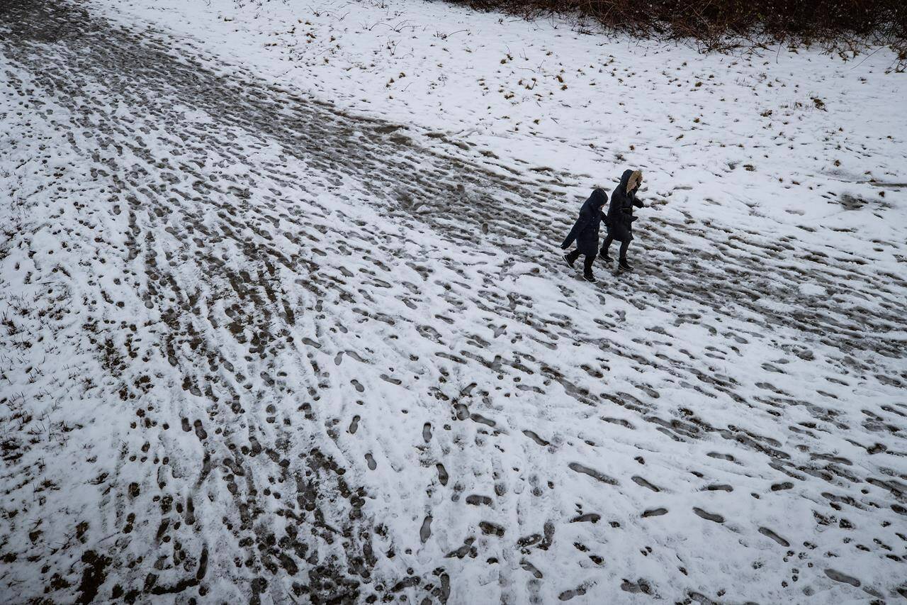 People walk on a snow-covered trail at Serpentine Fen Bird Sanctuary, in Surrey, B.C., on Monday, February 15, 2021. British Columbia residents are being urged to prepare for extremely cold temperatures, power outages and slick streets as a series of winter storm and freezing rain warnings covered most of the province Tuesday night. THE CANADIAN PRESS/Darryl Dyck