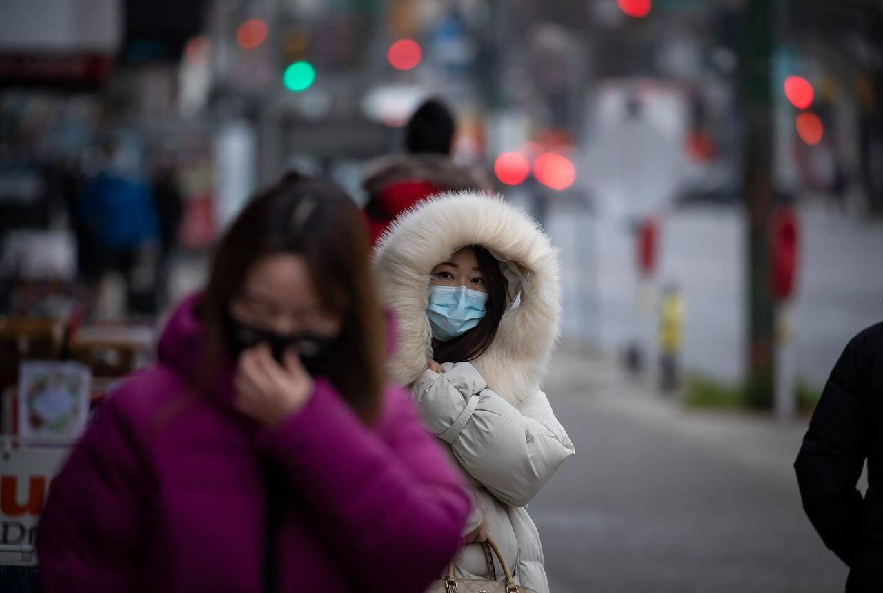 A person bundled up in a heavy jacket for the cold weather wears a face mask to curb the spread of COVID-19 in Vancouver, on Tuesday, Dec. 21, 2021. THE CANADIAN PRESS/Darryl Dyck