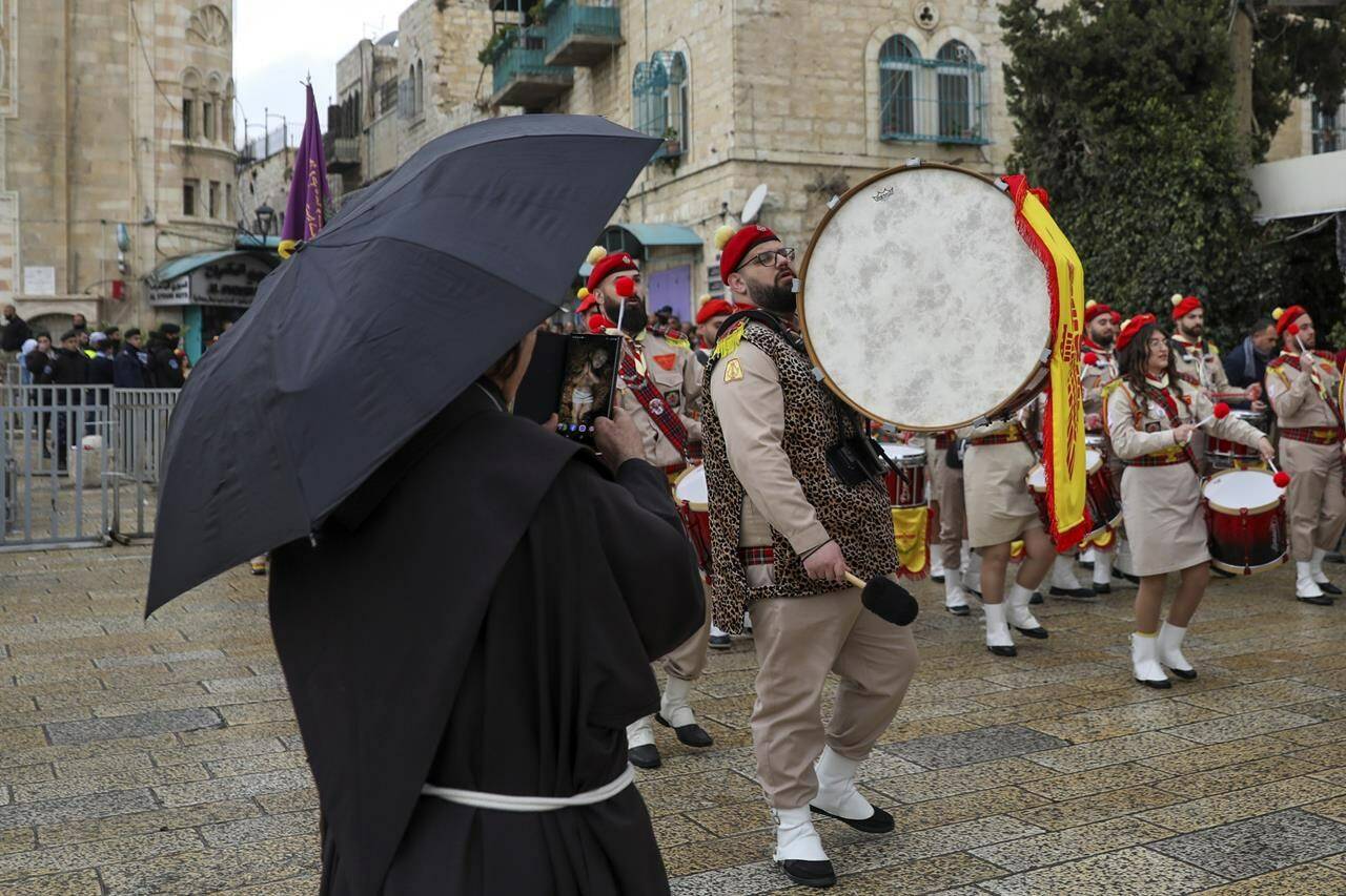Palestinian scout bands parade through Manger Square at the Church of the Nativity, traditionally believed to be the birthplace of Jesus Christ, during Christmas celebrations, in the West Bank city of Bethlehem, Friday, Dec. 24, 2021. The biblical town of Bethlehem is gearing up for its second straight Christmas Eve hit by the coronavirus with small crowds and gray, gloomy weather dampening celebrations Friday in the traditional birthplace of Jesus. (AP Photo/Mahmoud Illean)