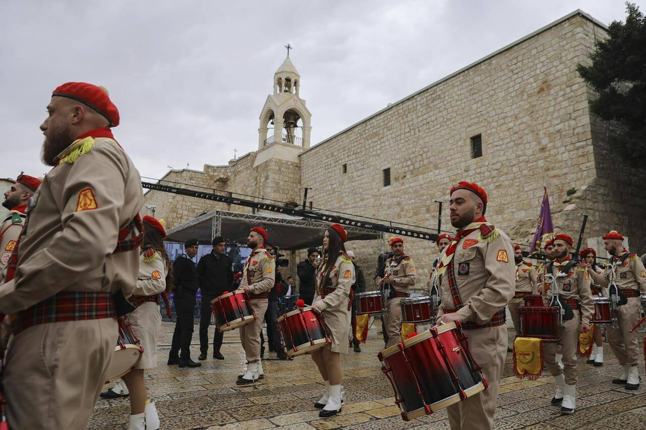 Palestinian scout band members parade through Manger Square at the Church of the Nativity, traditionally believed to be the birthplace of Jesus Christ, during Christmas celebrations, in the West Bank city of Bethlehem, Friday, Dec. 24, 2021. The biblical town of Bethlehem is gearing up for its second straight Christmas Eve hit by the coronavirus with small crowds and gray, gloomy weather dampening celebrations Friday in the traditional birthplace of Jesus. (AP Photo/Mahmoud Illean)