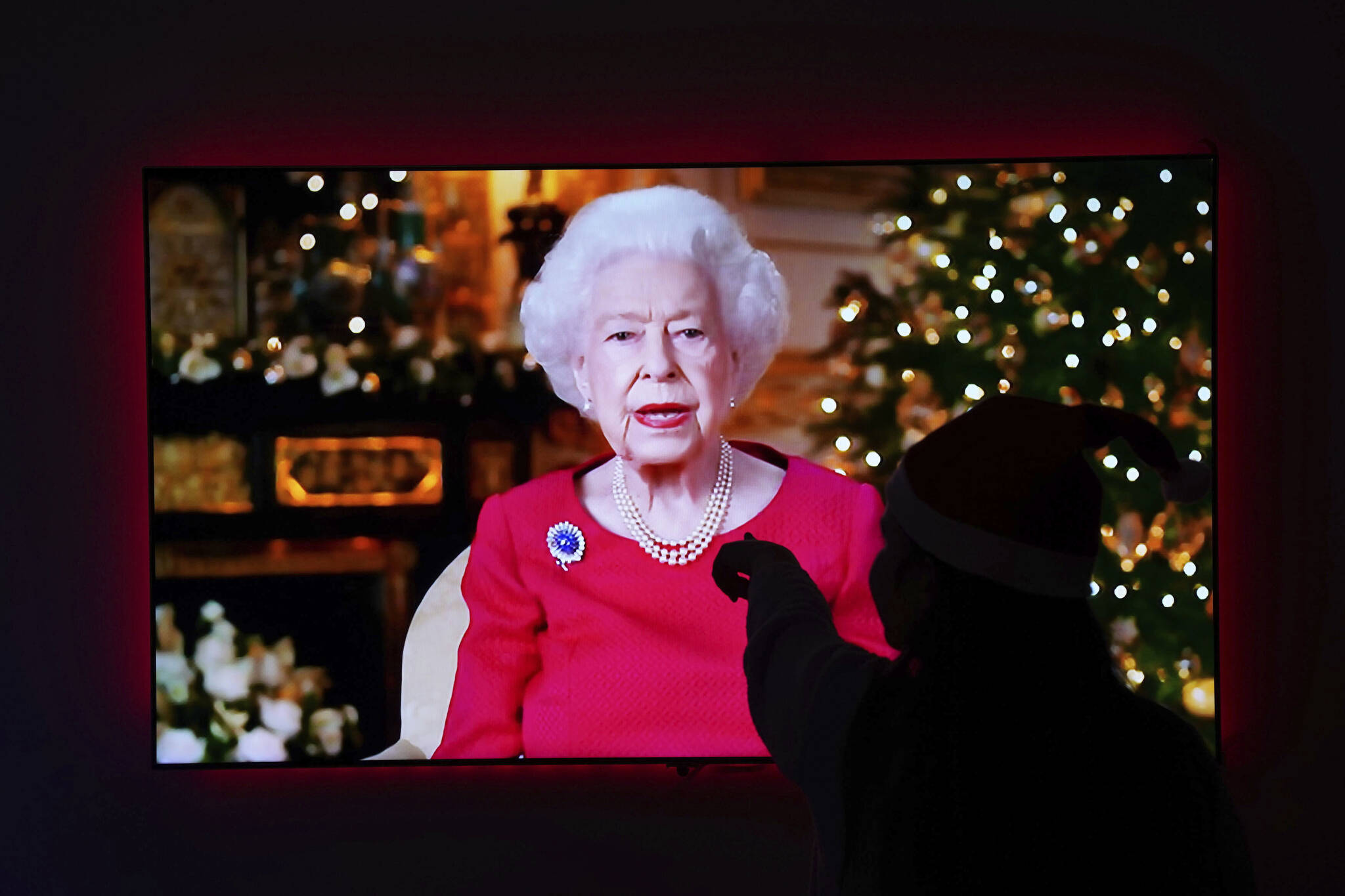 A child is silhouetted on the television screen of her home in Larbert, England, Saturday, Dec. 25, 2021 as she watches Queen Elizabeth II giving her annual Christmas broadcast from Windsor Castle. (Andrew Milligan/PA via AP)
