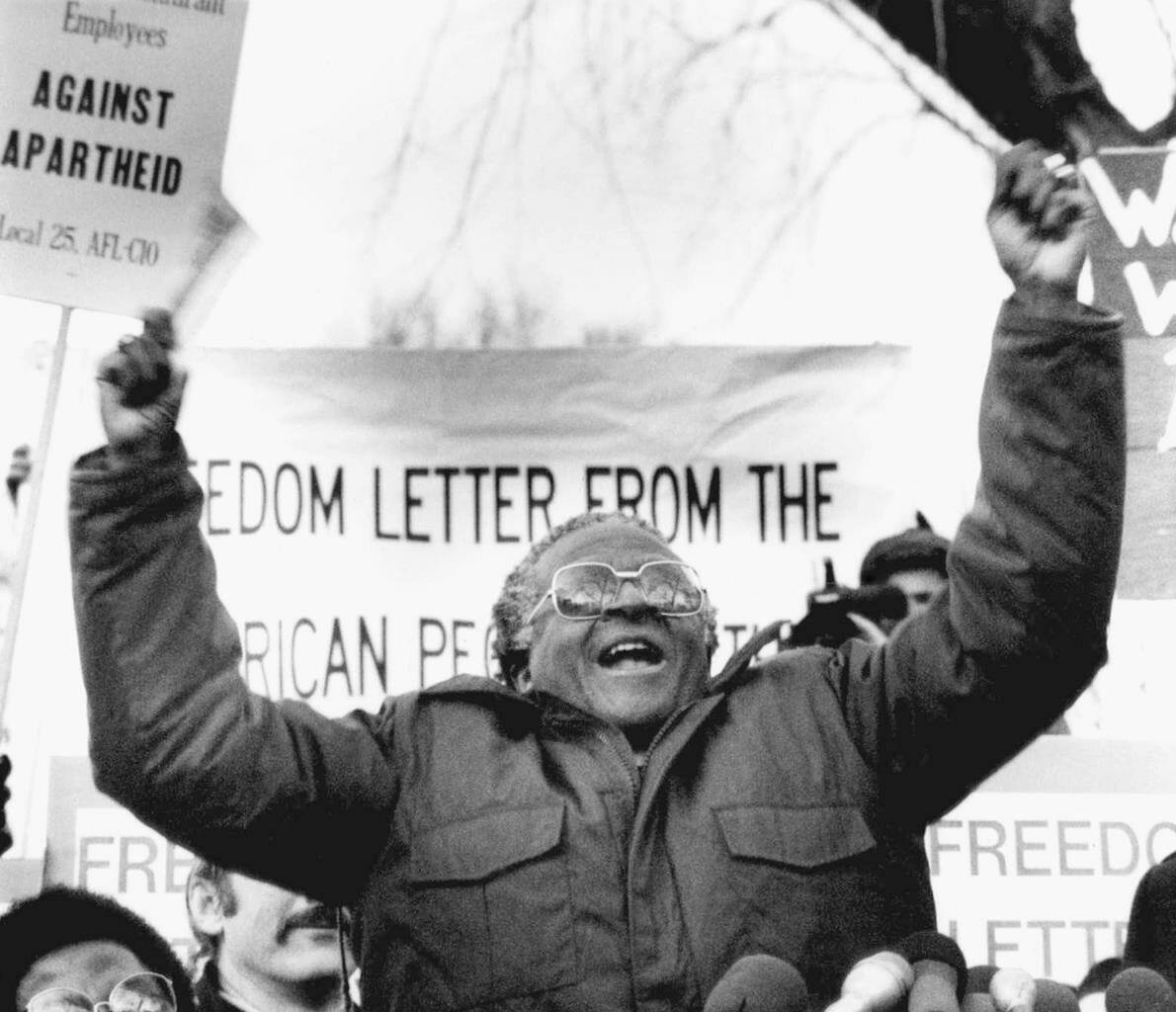 FILE - South African Bishop Desmond Tutu waves during a speech against apartheid, to a crowd of demonstrators, on Jan. 8, 1986, outside the South African Embassy in Washington. South Africa’s Nobel Peace Prize-winning activist for racial justice and LGBT rights and the retired Anglican Archbishop of Cape Town, has died at the age of 90, it was announced on Sunday, Dec. 26, 2021. An uncompromising foe of apartheid, South Africa’s brutal regime of oppression again the Black majority, Tutu worked tirelessly, but non-violently, for its downfall. (AP Photo/Dennis Cook, File)