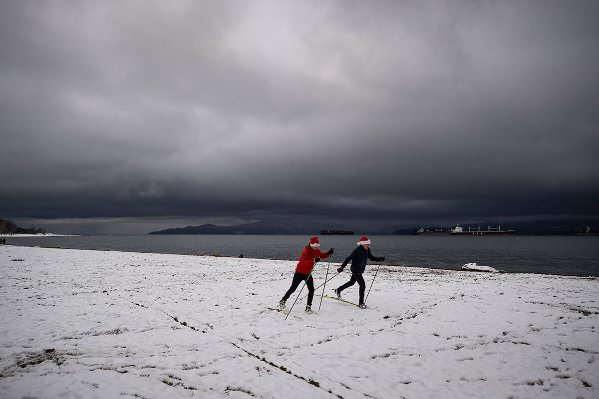 People cross-country ski at Locarno Beach after an overnight snowfall in Vancouver, B.C., Saturday, Dec. 25, 2021. THE CANADIAN PRESS/Darryl Dyck