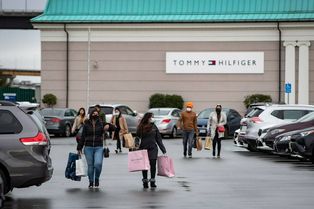 People carry shopping bags as they walk to vehicles in the parking lot at McArthur Glen Designer Outlet, on Boxing Day in Richmond, B.C., Saturday, Dec. 26, 2020. Muted sales, quieter stores, small groups of people allowed in to maintain capacity limits due to the pandemic and “we’re hiring” signs greeted Boxing Day shoppers seeking bargains. THE CANADIAN PRESS/Darryl Dyck