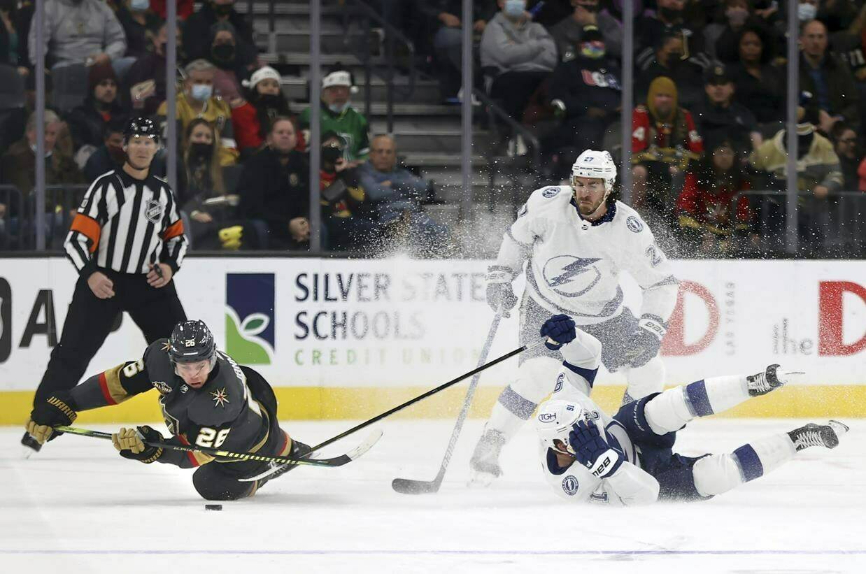 Vegas Golden Knights center Mattias Janmark (26) eyes the puck after colliding withTampa Bay Lightning center Steven Stamkos (91) during the third period of an NHL hockey game Tuesday, Dec. 21, 2021, in Las Vegas. (AP Photo/L.E. Baskow)