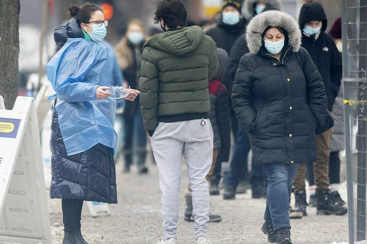 People wait in line at a COVID-19 testing and vaccination site in Montreal, Wednesday, Dec. 29, 2021. Ontario and Quebec are both reporting new COVID-19 case records today as Canadian provinces explore changing their isolation rules to keep health systems afloat amid an unprecedented wave of infections. THE CANADIAN PRESS/Graham Hughes