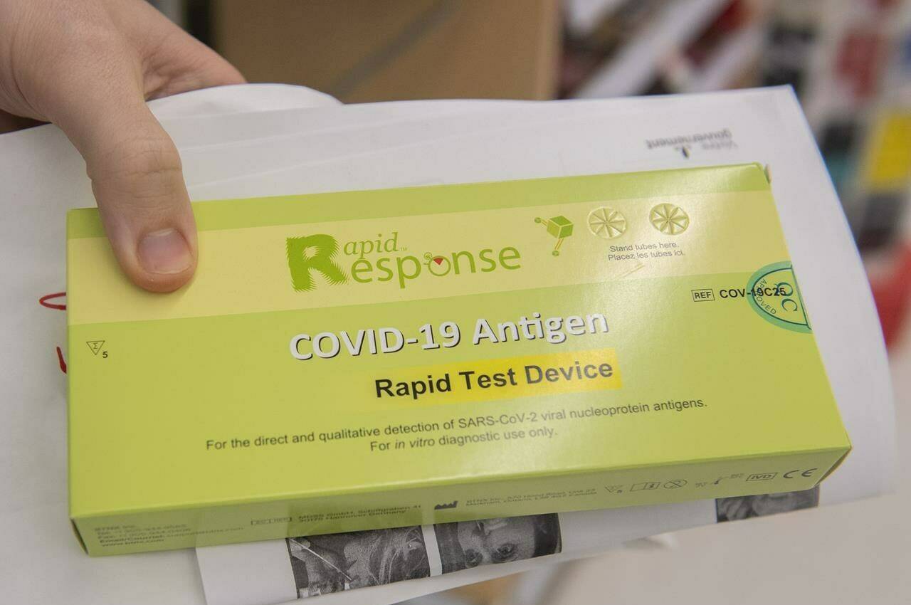 A man displays his COVID-19 rapid test kit after receiving it at a pharmacy in Montreal, Monday, December 20, 2021. Canadian business and labour groups are at odds over the preferred isolation times for people who have tested positive for COVID-19. THE CANADIAN PRESS/Graham Hughes