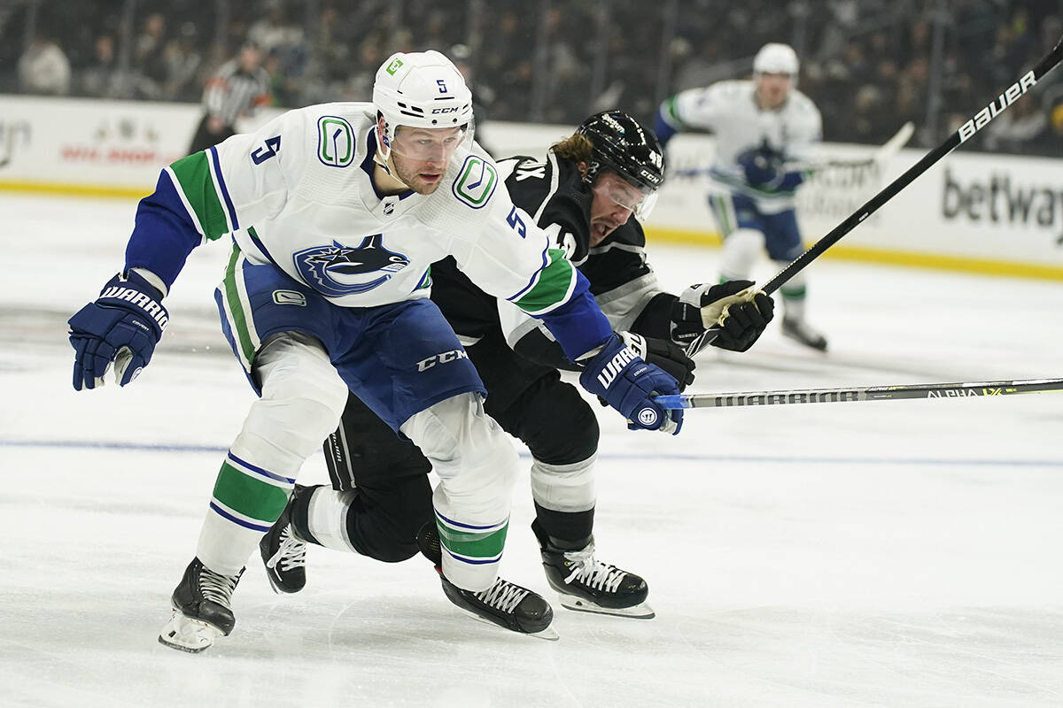 Vancouver Canucks’ Tucker Poolman, left, and Los Angeles Kings’ Brendan Lemieux chase the puck during second period of an NHL hockey game Thursday, Dec. 30, 2021, in Los Angeles. (AP Photo/Jae C. Hong)