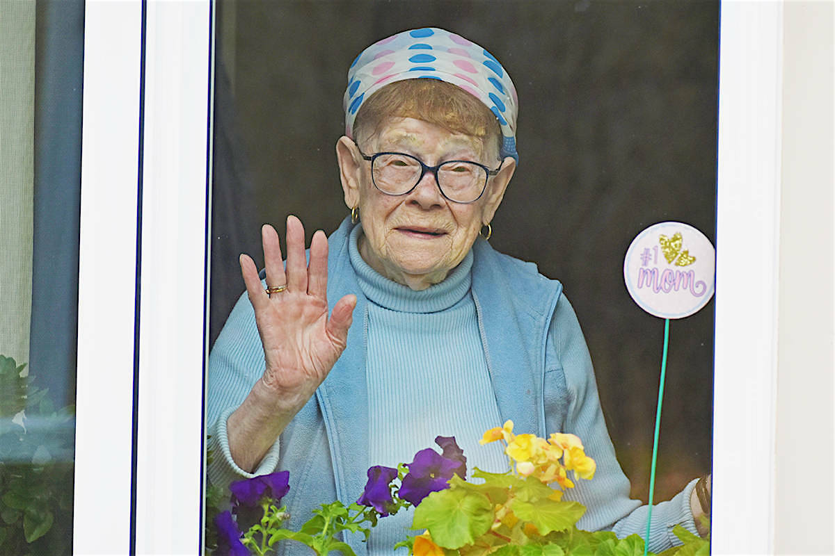 Rose Sawka, 91, waves to her son through the window of Acropolis Manor. She has been looking through the glass for contact since a COVID-19 outbreak at the long-term health and care home care facility on Jan. 19, 2021, locked the world outside. (K-J Millar/The Northern View)