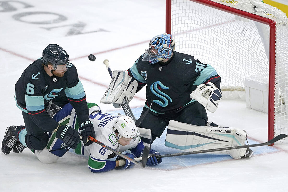 Seattle Kraken goaltender Philipp Grubauer, right, makes a stop as Kraken defenceman Adam Larsson (6) and Vancouver Canucks centre Matthew Highmore (15) crash against him during the second period of an NHL hockey game Saturday, Jan. 1, 2022, in Seattle. (AP Photo/Ted S. Warren)