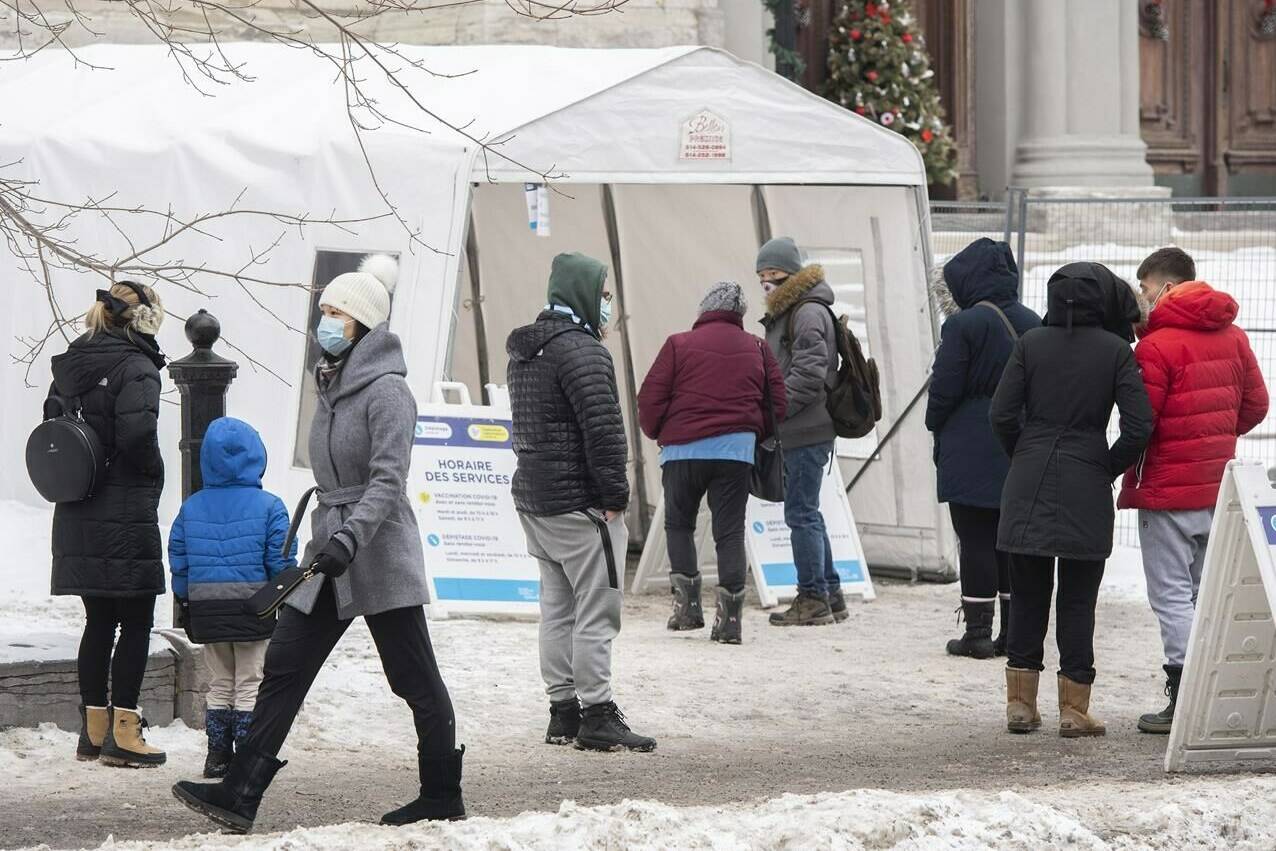 People wait in line at a COVID-19 testing and vaccination site in Montreal, Wednesday, December 29, 2021. Provinces are putting new measures in place to deal with an Omicron-fuelled rise in COVID-19 cases and hospitalizations, including delaying in-person schooling in Ontario by two weeks and bringing in the military to help Quebec speed up its third-dose vaccination program. THE CANADIAN PRESS/Graham Hughes