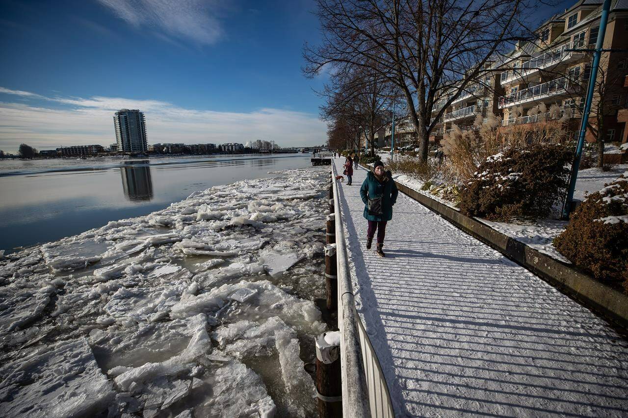 Ice floes build up on the Fraser River as people walk along the waterfront in New Westminster, B.C., on Tuesday, Dec. 28, 2021. THE CANADIAN PRESS/Darryl Dyck