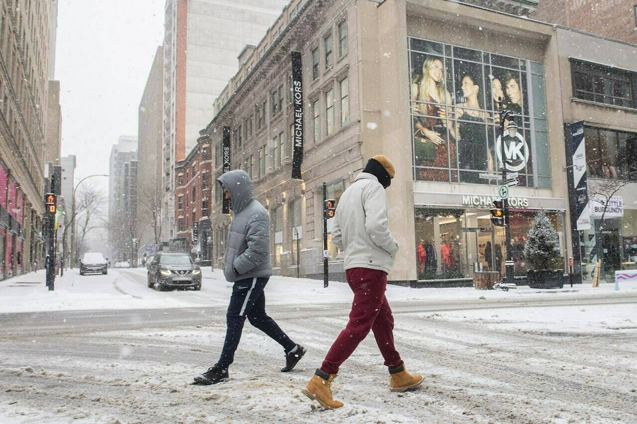 People walk along Ste-Catherine Street in Montreal, Sunday, January 2, 2022, as the COVID-19 pandemic continues in Canada. Some measures put in place by the Quebec government, including the closure of stores to help curb the spread of COVID-19 in the province. THE CANADIAN PRESS/Graham Hughes