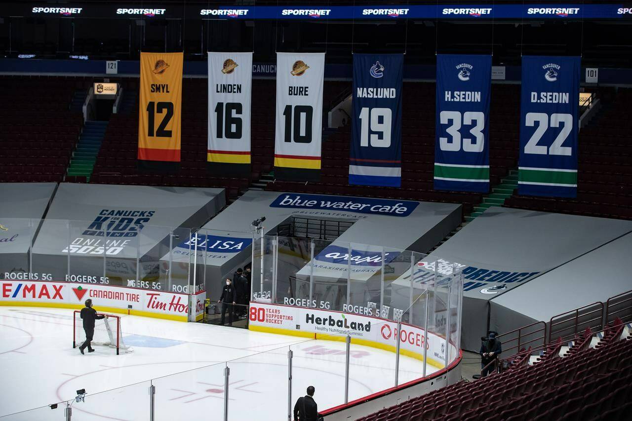 An arena worker removes the net from the ice after the Vancouver Canucks and Calgary Flames NHL hockey game was postponed due to a positive COVID-19 test result, in Vancouver, B.C., Wednesday, March 31, 2021. THE CANADIAN PRESS/Darryl Dyck