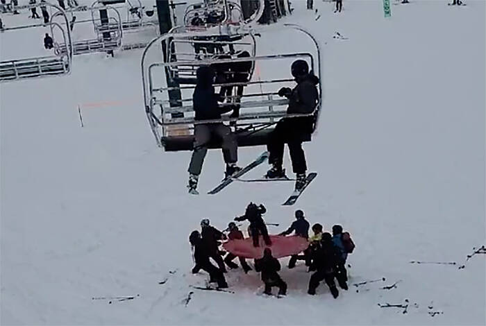 Mount Washington employees and skiers collaborate to set up a safety net under the Sunrise chairlift and catch a young person who was dangling from their chair. Screenshot