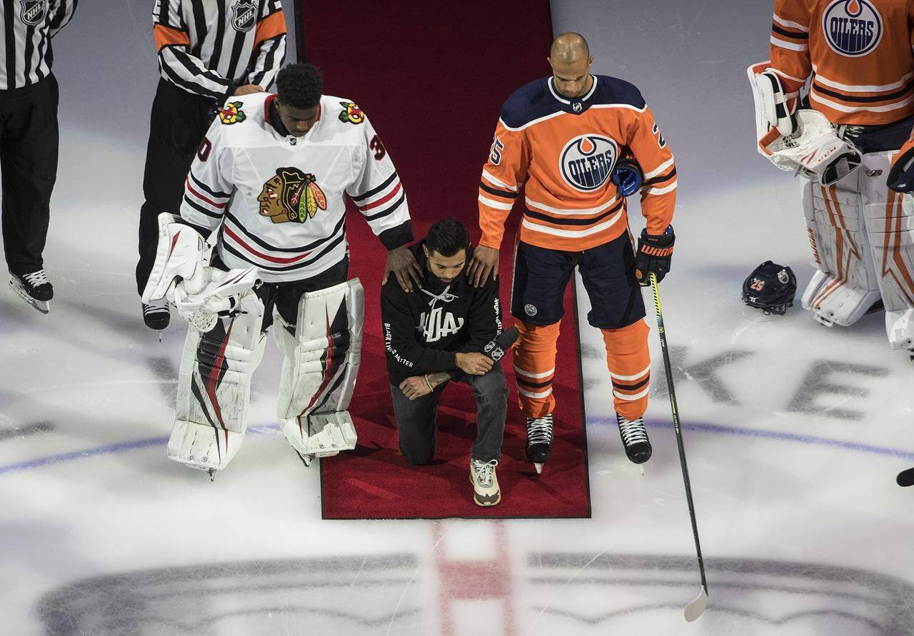 FILE - In this Aug. 1, 2020, file photo, Minnesota Wild's Matt Dumba takes a knee during the national anthem flanked by Chicago Blackhawks' Malcolm Subban, left, and Edmonton Oilers' Darnell Nurse, before an NHL hockey Stanley Cup playoff game in Edmonton, Alberta. Dumba, former NHL player Akim Aliu, Colorado’s Nazem Kadri, Toronto’s Wayne Simmonds and Florida’s Anthony Duclair are members of the recently formed Hockey Diversity Alliance. (Jason Franson/The Canadian Press via AP, File)