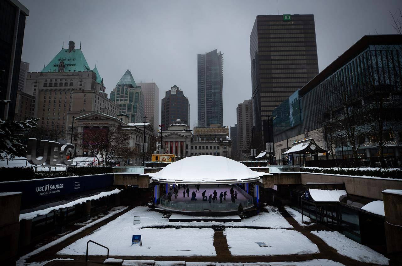 People skate under the snow-covered dome roof at the Robson Square ice rink as rain falls in Vancouver, B.C., Thursday, Jan. 6, 2022. Weather warnings blanket most of northern British Columbia as a Pacific frontal system brings heavy snow and extreme cold, however conditions are less severe further south. THE CANADIAN PRESS/Darryl Dyck