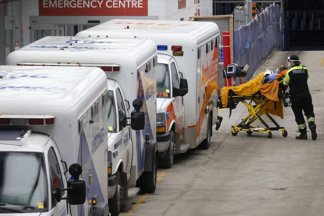 Paramedics wheel a patient past ambulances outside a Toronto Hospital on Wednesday, Jan. 5, 2022. Hospitals in several parts of Canada are straining under the weight of the Omicron variant of COVID-19, with Quebec hospitalizations reaching an all-time high on Sunday and Ontario’s admissions to intensive care units surging past the 400 mark. THE CANADIAN PRESS/Chris Young