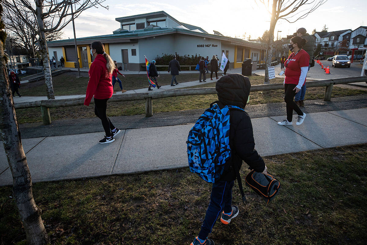 A student arrives at school as teachers dressed in red participate in a solidarity march to raise awareness about cases of COVID-19 at Ecole Woodward Hill Elementary School, in Surrey, B.C., on Tuesday, February 23, 2021. THE CANADIAN PRESS/Darryl Dyck