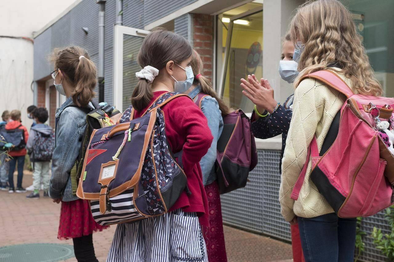 File - Students attend the first day of school for the 2021-2022 year at Gounod Lavoisier Primary school, Lille, northern France, Thursday, Sept. 2 2021. Less than two weeks after the winter term started, French teachers are already exhausted by the pressures of surging COVID-19 cases and they are walking out in nationwide strike organized by their unions to protest virus-linked class disruptions and ever-changing isolation rules. (AP Photo/Michel Spingler, File)