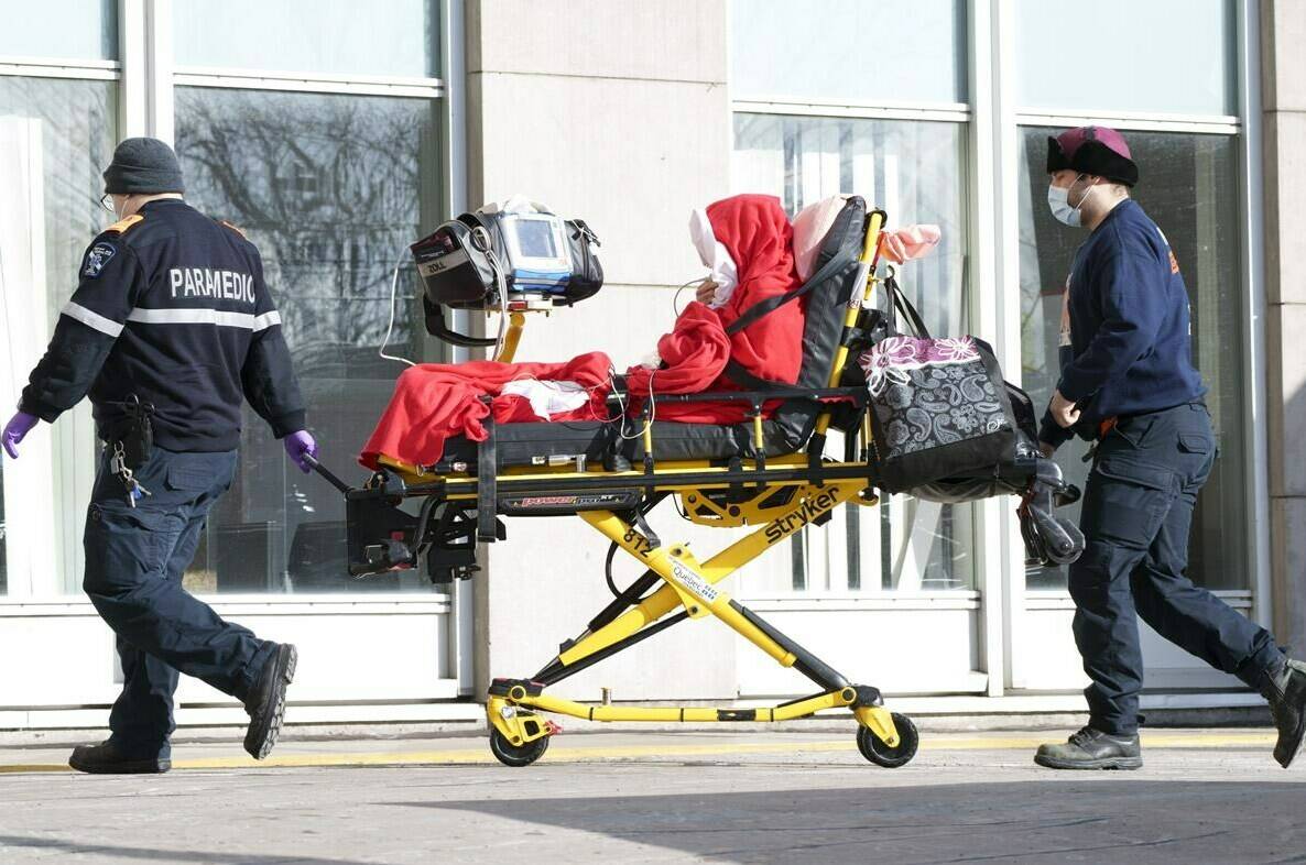 Paramedics transfer a patient to a hospital in Montreal, on Monday, January 10, 2022. With COVID-19 cases putting Canada’s hospitals at or near capacity, Quebec’s unprecedented plan to tax adult residents who refuse to be vaccinated against the virus is coming under fire. THE CANADIAN PRESS/Paul Chiasson