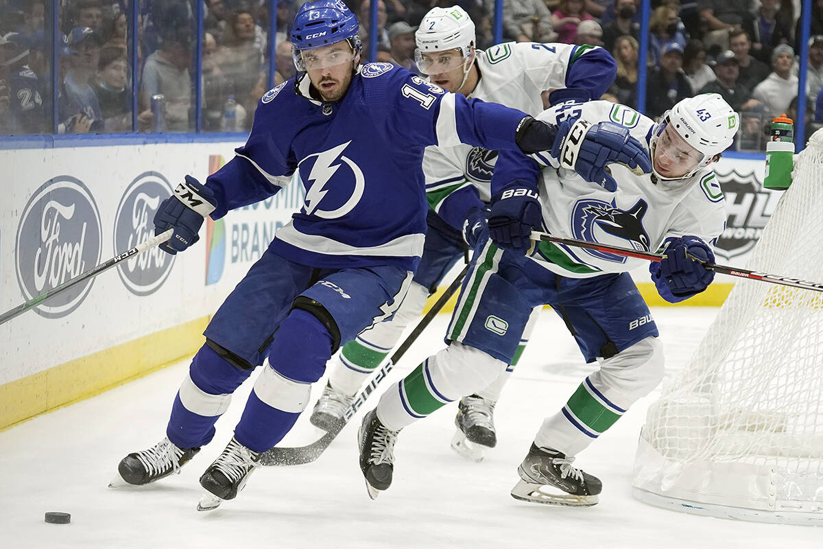 Tampa Bay Lightning left wing Boris Katchouk (13) pushes away Vancouver Canucks defenceman Quinn Hughes (43) as he moves the puck during the second period of an NHL hockey game Thursday, Jan. 13, 2022, in Tampa, Fla. (AP Photo/Chris O’Meara)