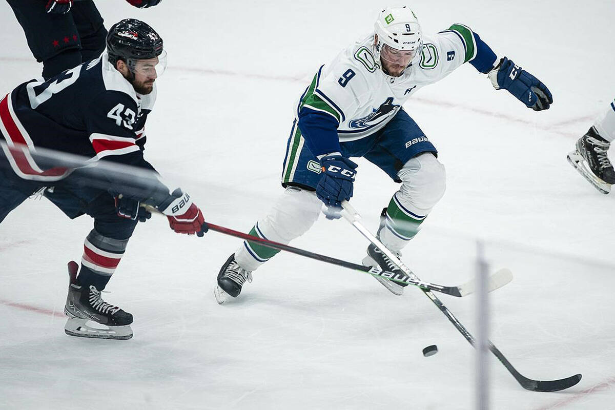 Washington Capitals right wing Tom Wilson (43) moves the puck past Vancouver Canucks centre J.T. Miller (9) during the first period of an NHL hockey game against the Vancouver Canucks, Sunday, Jan. 16, 2022, in Washington. (AP Photo/Al Drago)
