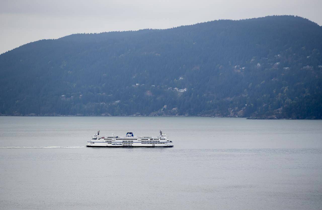 The B.C. Ferries vessel Queen of Surrey passes Bowen Island while traveling on Howe Sound from Horseshoe Bay to Langdale, B.C., on Friday, April 23, 2021. A BC Ferries spokesman is encouraging passengers to check online for possible service disruptions before heading to a terminal. THE CANADIAN PRESS/Darryl Dyck