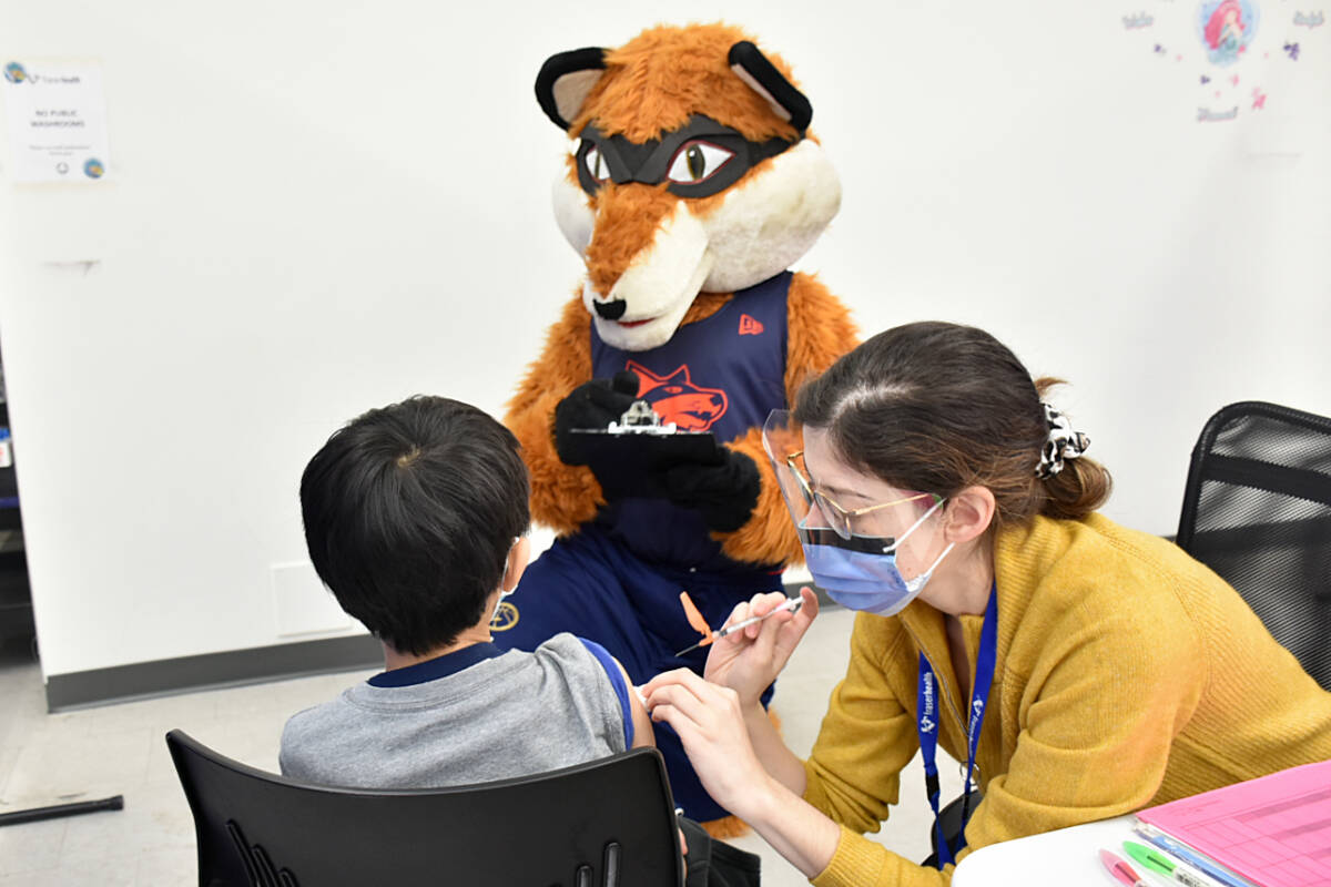 Fraser Valley Bandits mascot Berry helps out at Maple Ridge COVID-19 vaccine clinic at Haney Place Mall on Tuesday, as a little boy received his jab from pharmacist immunizer Ana Costa. Berry was handing out stickers. (Colleen Flanagan/Maple Ridge News)