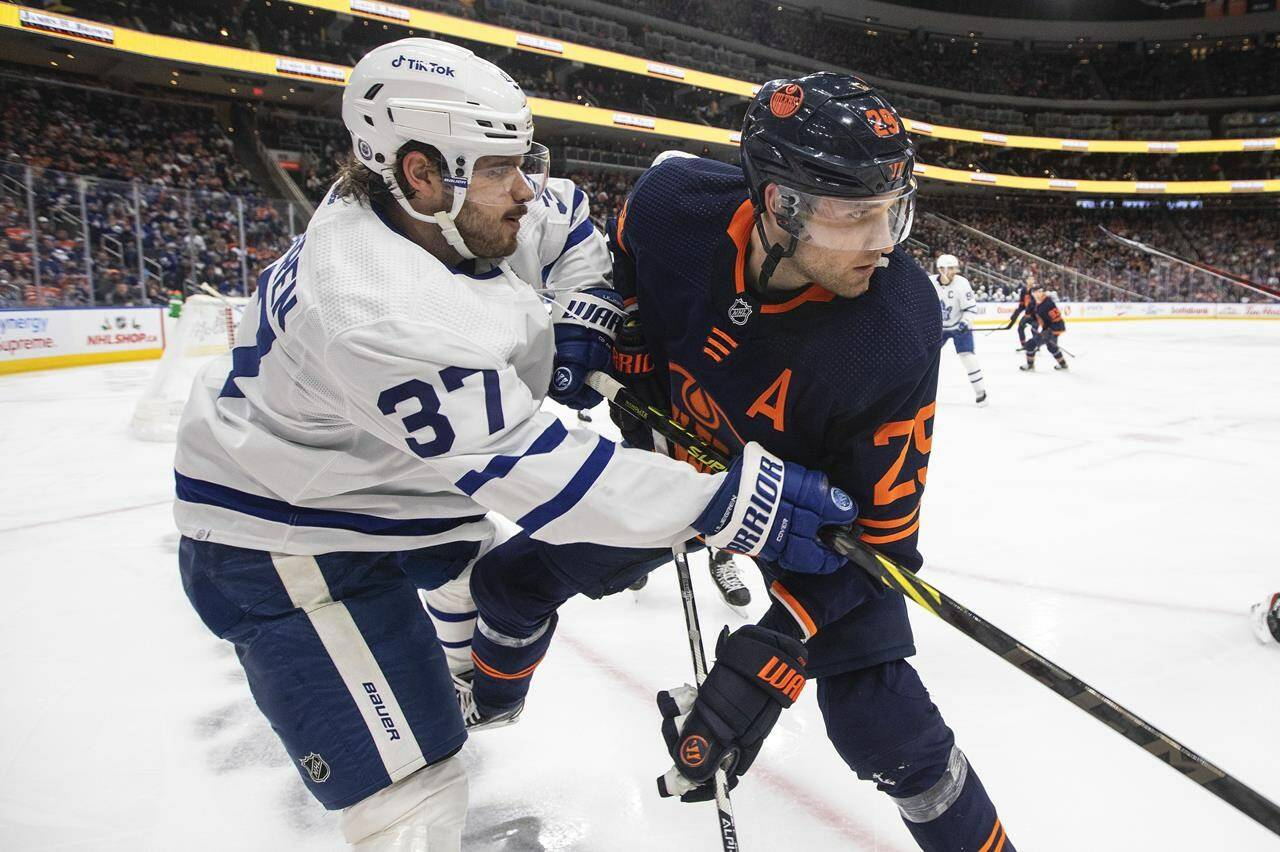 Toronto Maple Leafs' Timothy Liljegren (37) and Edmonton Oilers' Leon Draisaitl (29) battle for the puck during second period NHL action in Edmonton on Tuesday, December 14, 2021.THE CANADIAN PRESS/Jason Franson