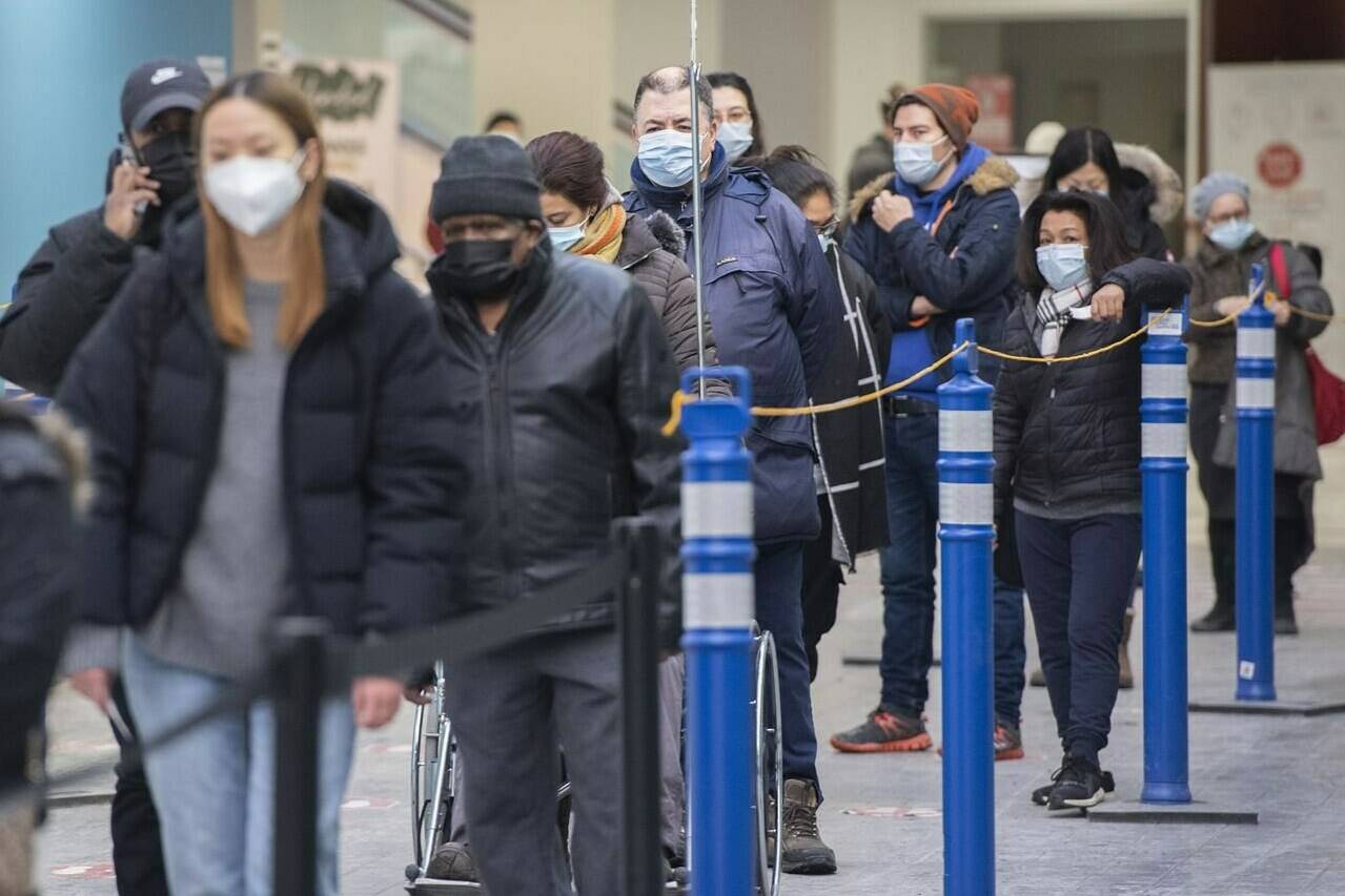 People wait in line at a COVID-19 vaccination site in Montreal, Sunday, Jan. 16, 2022, as the COVID-19 pandemic continues in Canada. The Omicron-fuelled fifth wave of the COVID-19 pandemic appears to be peaking in some provinces, while others say the worst is likely still to come. THE CANADIAN PRESS/Graham Hughes