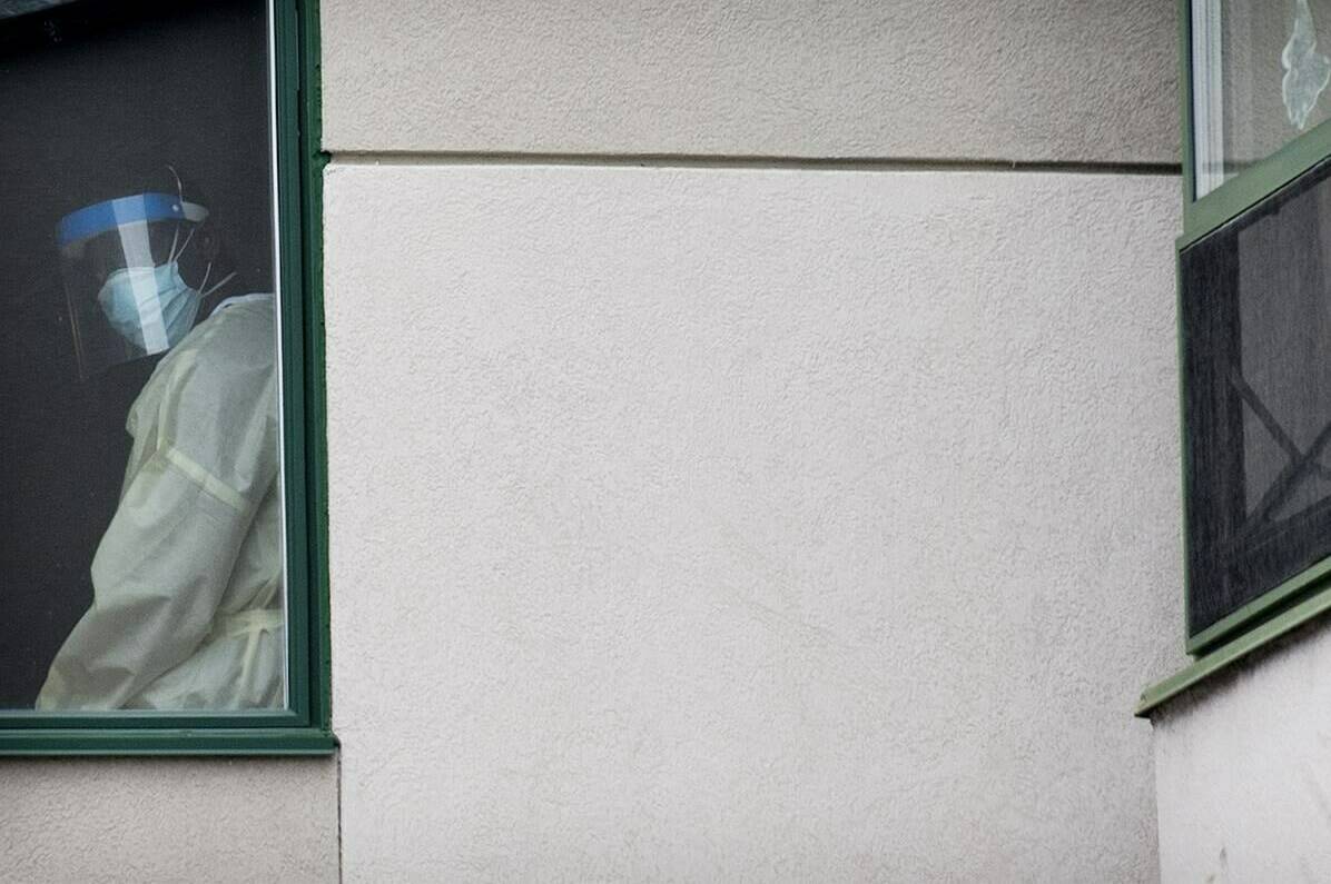 A health-care worker looks out of a window at Maison Herron, a long-term care home in the Montreal suburb of Dorval, on Saturday, April 11, 2020. The physical and mental health impacts of isolation periods are high for seniors living in care facilities.THE CANADIAN PRESS/Graham Hughes