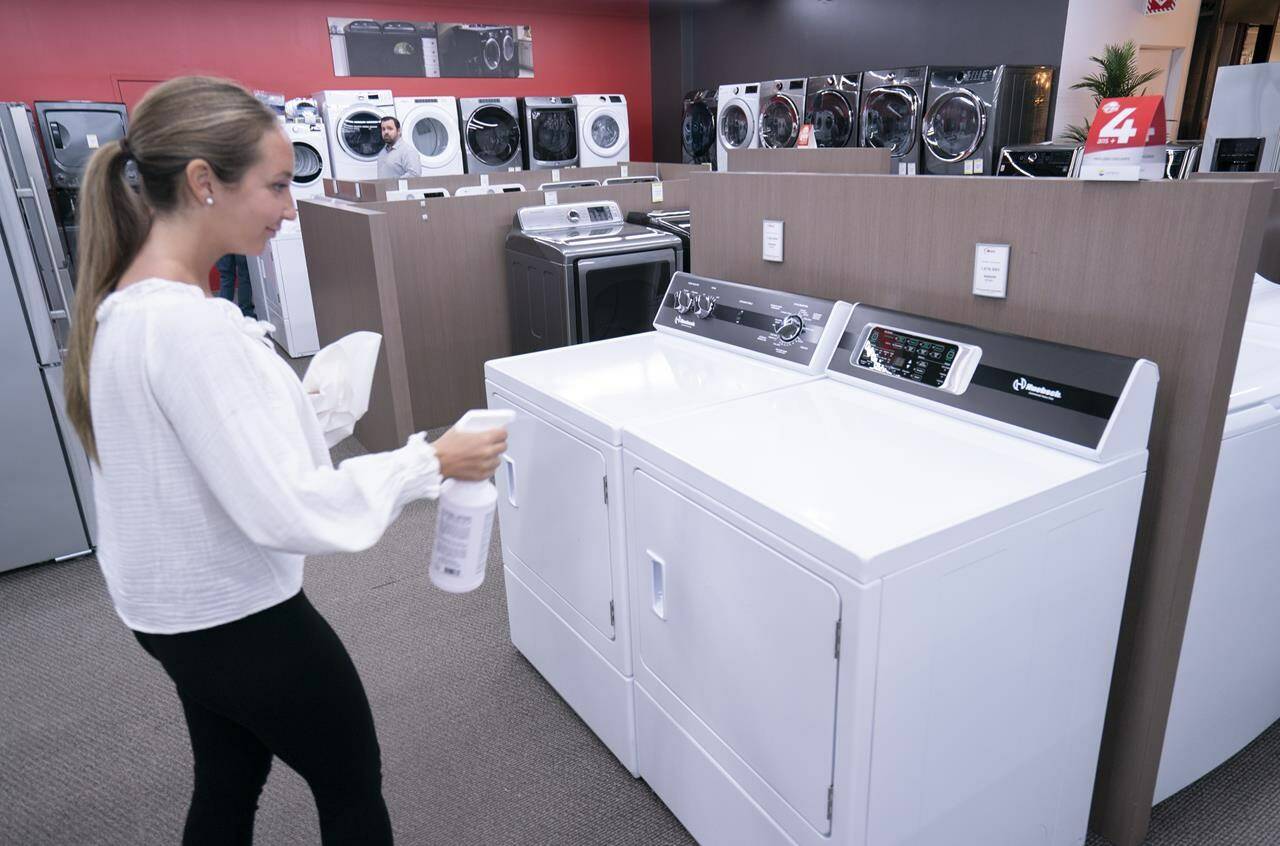 A sales clerk sanitizes appliances at a furniture store in St-Jean-sur-Richelieu, Que. on Monday, May 4, 2020. THE CANADIAN PRESS/Paul Chiasson