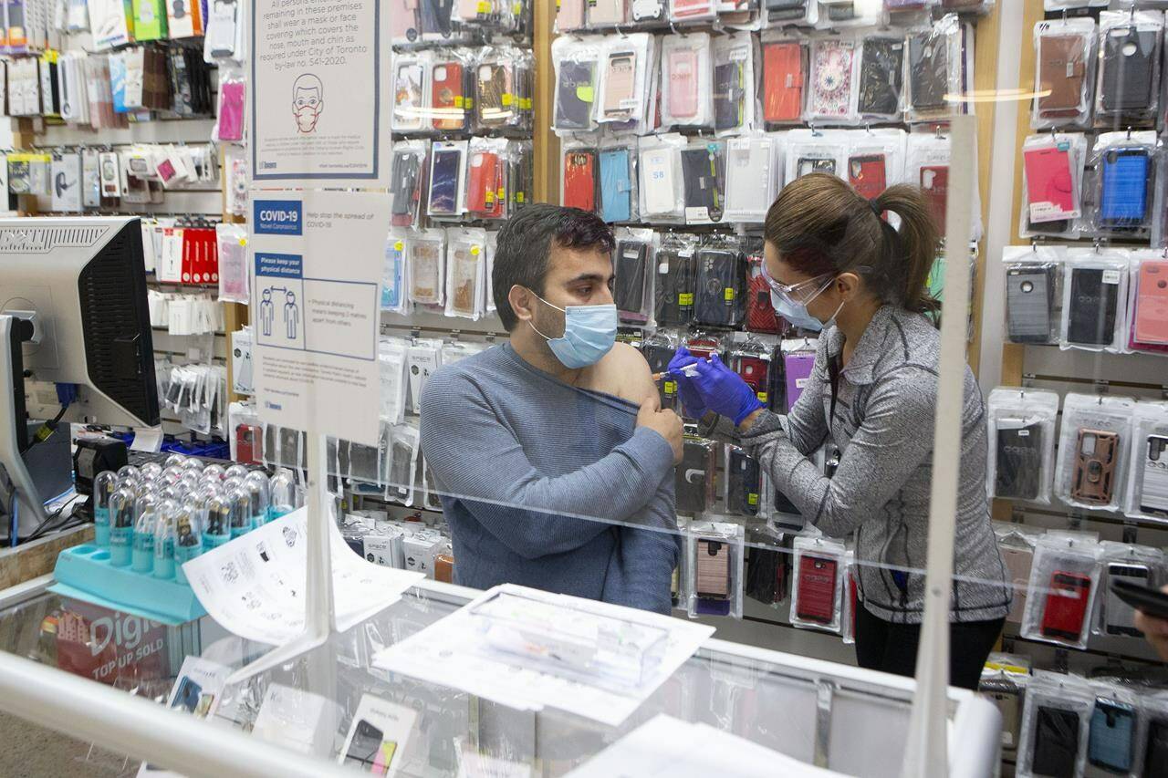 Sayed Rahman owner of Phone Cards Plus at the Jane and Finch Mall, is given a COVID-19 vaccine by Nurse Sandra Bernal during a mobile clinic, operated by Black Creek Community Health Centre, in Toronto, on Thursday, January 13, 2022.THE CANADIAN PRESS/Chris Young