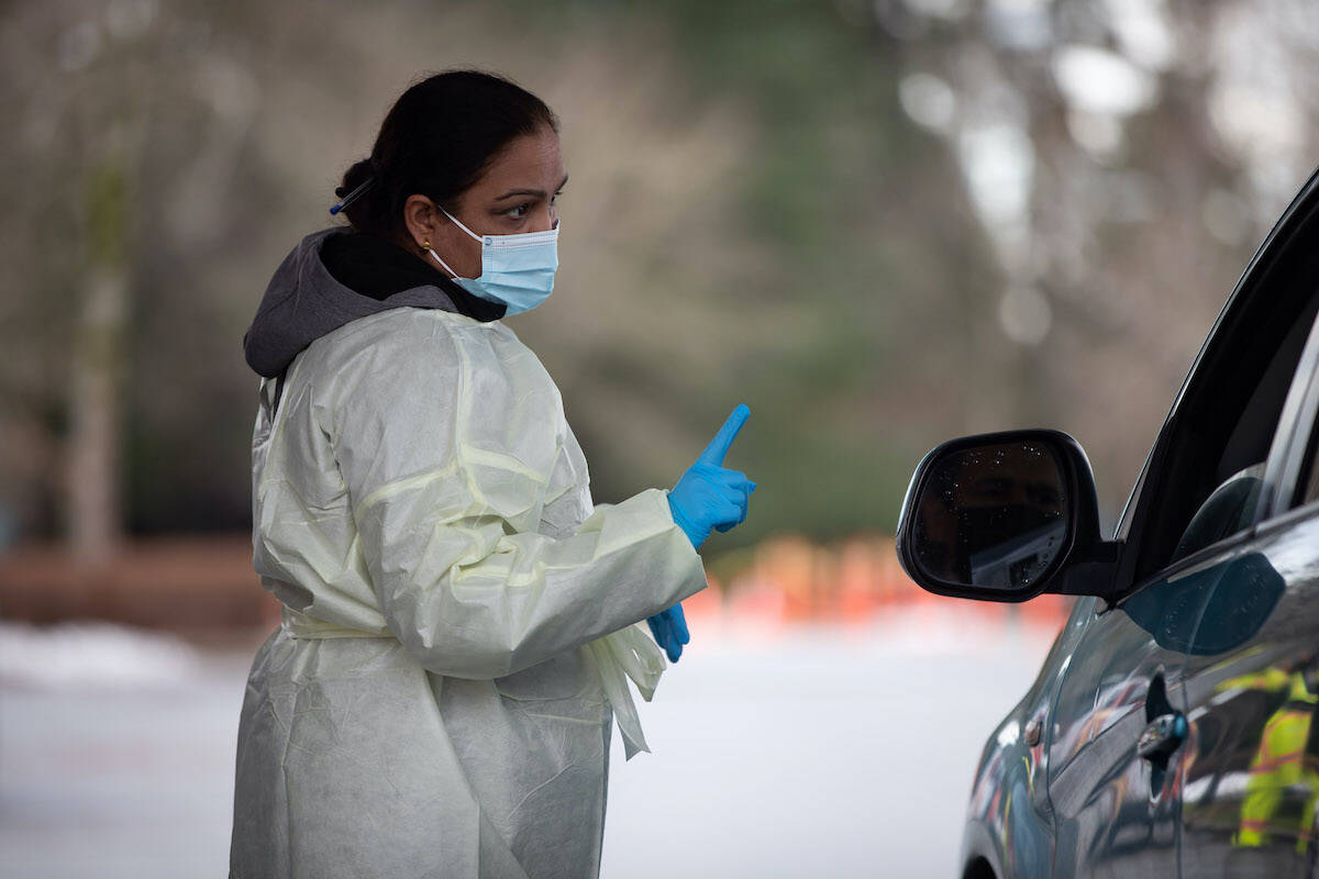 Fraser Health employee Amarjeet Jammu speaks with a motorist after giving them a COVID-19 rapid test kit at a drive-thru pick up site in Surrey, B.C., on Thursday, January 20, 2022. THE CANADIAN PRESS/Darryl Dyck