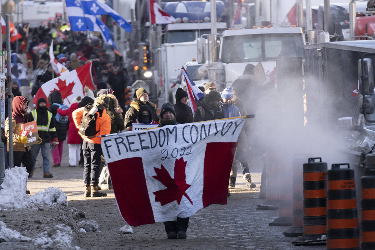 Protesters participating in a cross-country truck convoy protesting measures taken by authorities to curb the spread of COVID-19 and vaccine mandates walk near Parliament Hill in Ottawa on Saturday, Jan. 29, 2022. THE CANADIAN PRESS/Adrian Wyld