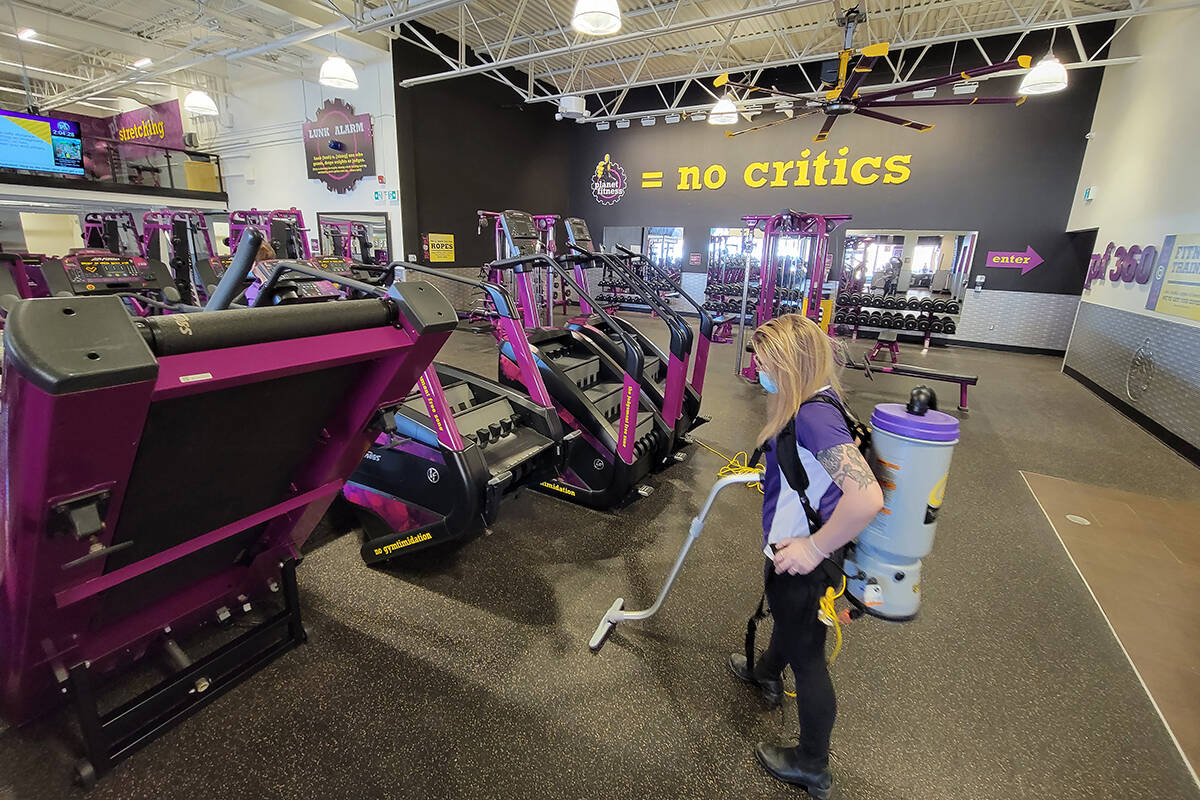 An employee helps clean a Planet Fitness gym location in Bowmanville, Ont. on Friday Jan. 28, 2022. Restaurants, gyms, cinemas and many other businesses in Ontario are set to open their doors once again on Monday to fully vaccinated patrons, but with COVID-19 levels likely just past a peak, some question if “fully vaccinated” should be redefined. THE CANADIAN PRESS/Doug Ives