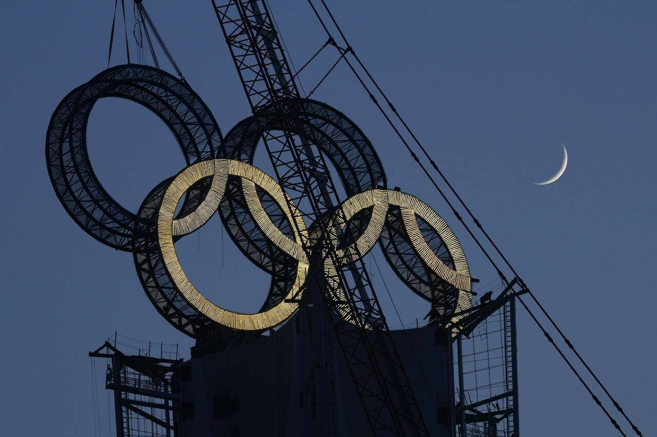 A worker labours to assemble the Olympic Rings onto of a tower on the outskirts of Beijing, China on Jan. 5, 2022. (AP Photo/Ng Han Guan, File)