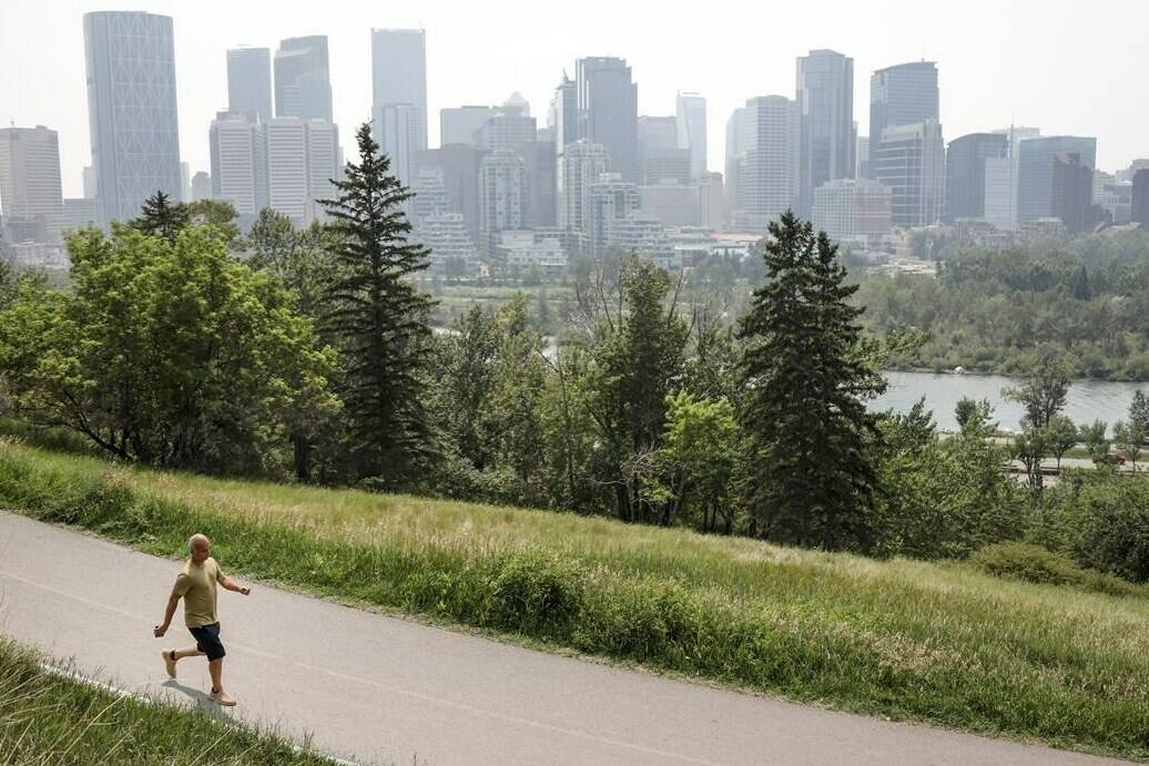 A pedestrian walks on a trail with the Calgary skyline in the background on Thursday, July 15, 2021.Once Canada’s boomtown, the latest census from Statistics Canada suggests Wild Rose Country is becoming just another Canadian province. THE CANADIAN PRESS/Jeff McIntosh