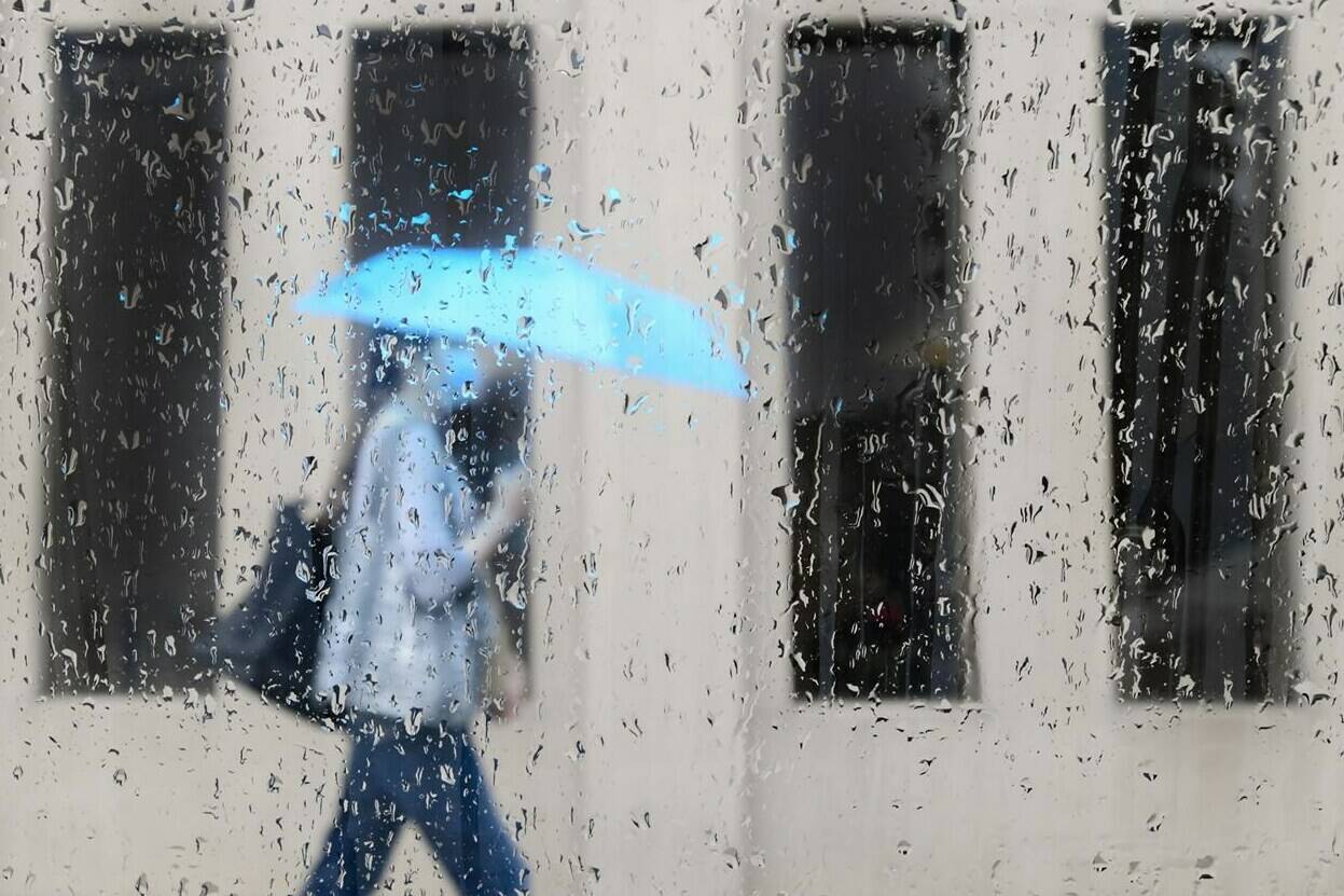 A pedestrian walks alongside businesses on a rainy day while wearing a protective mask during the COVID-19 pandemic in Toronto on Friday, June 18, 2021. There is a noticeable decline in how trusting Canadians are of their leaders and institutions as the pandemic drags on, and it’s particularly striking among those who remain anxious or stressed about COVID-19, a new survey suggest. THE CANADIAN PRESS/Nathan Denette